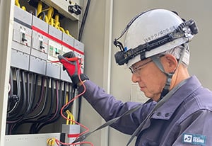 電気管理技術者が現場でパネルを点検する様子